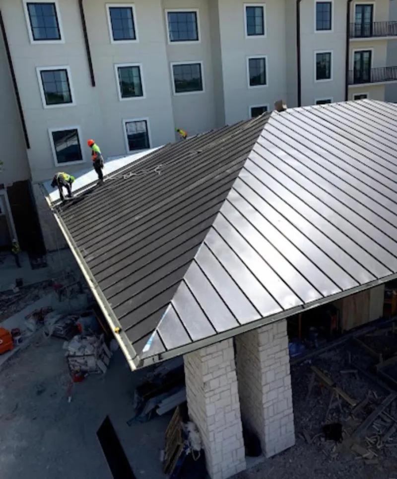 Crew installing standing seam metal roof panels on a commercial project in Framingham